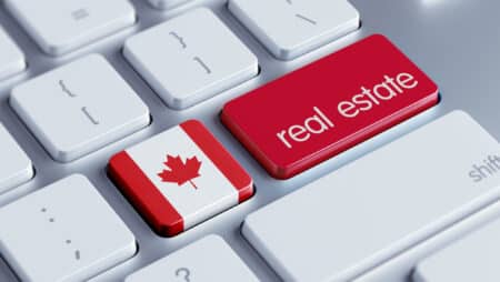 Closeup on a computer keyboard shows two red and white buttons; one with the Canadian-flag maple leaf, and the other reading “real estate.”